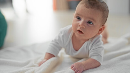 Newborn baby on soft blanket lifts head and props on forearm during tummy time in building  curiosity bonding. © Krakenimages.com
