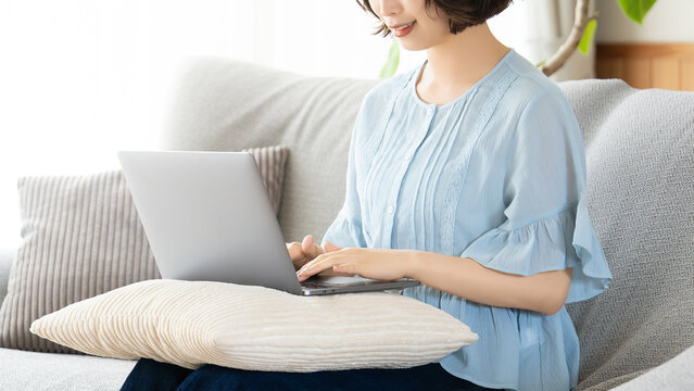 リビングのソファでノートパソコンを使う女性, Woman Using a Laptop on a Sofa in the Living Room