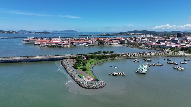 Cinematic drone footage flying from the Cinta Costera waterfront beside Panama City's famous Fish Market (Mercado de Mariscos) toward the historic Casco Viejo. Beautiful aerial panorama 