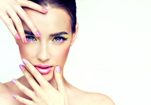 Beautiful model woman with a fashion makeup. Girl spring  pink and lilac manicure nails . Summer image .Make-up,Cosmetology and spa. Care for hands and cosmetics , cream and nail polish