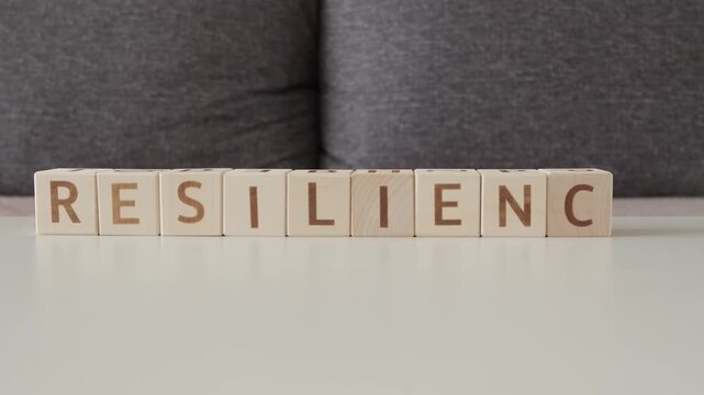 motivational word resilience, laying out  by hand from letters on wooden cubes, slow motion
