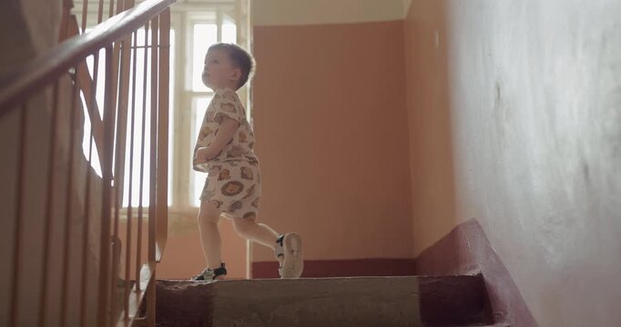 Young kid going up stairs inside an old residential house hallway, slow motion