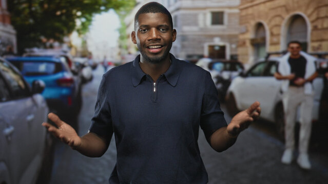 Man showing open hands and speaking while looking aside on a busy city street with parked cars and stone buildings; curiosity conversation.
