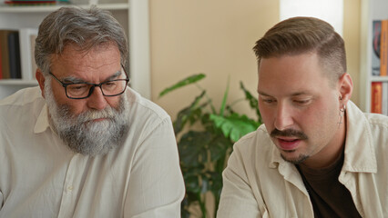 Two men looking at smartphone, one pointing finger to screen in building; focused collaboration...