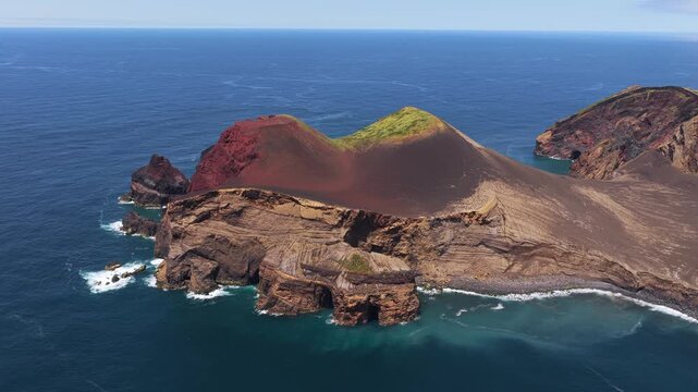 Aerial view of the dramatic volcanic landscape of Capelinhos with its unique red and black rock formations surrounded by the Atlantic Ocean in Capelo, Azores, Portugal.