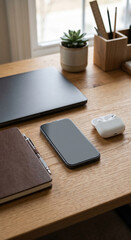 Naklejka premium Home office desk technology details with laptop and phone, home office desk close view showing earbuds, notebook, plant and pencil cup