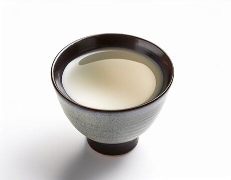 a traditional japanese sake cup filled with clear sake isolated on white background