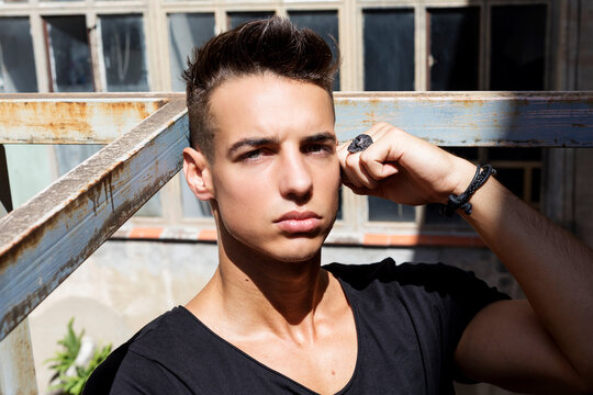 Serious young man posing in sunlight outdoors