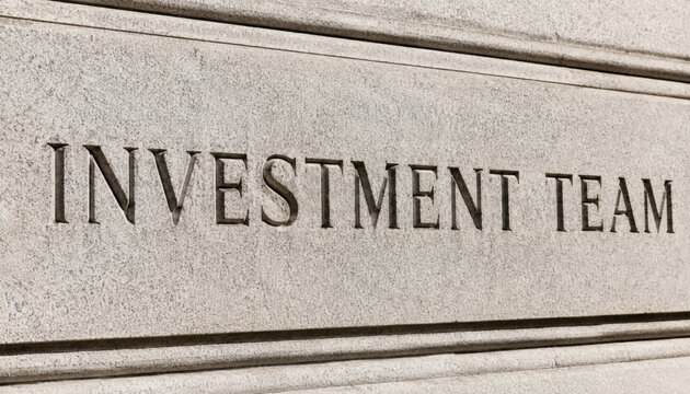 Close-up of engraved sign reading investment team on stone wall