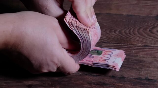 Close up of male hands counting a stack of five thousand Kazakhstani tenge banknotes