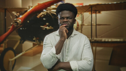 Man hand on chin in museum building beside vintage airplane propeller, looking pensive and studying the display  thoughtful. © Krakenimages.com