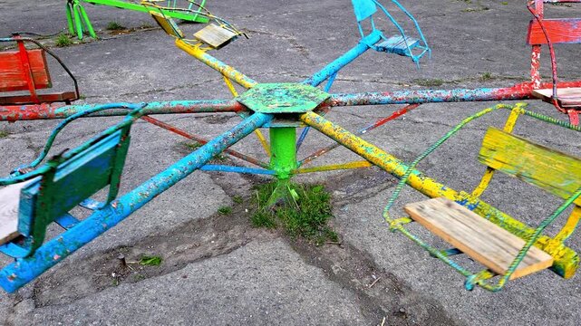 Empty colorful carousel spinning slowly on an old cracked playground