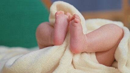 Newborn baby girl feet touching toes on cream fleece blanket in studio setup with soft swaddle  tender serenity. © Krakenimages.com