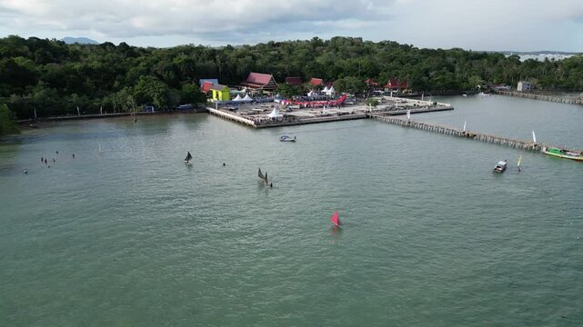 Aerial view of a coastal pier with traditional sailboats Perahu Jong and small boats on the water in Indonesia.