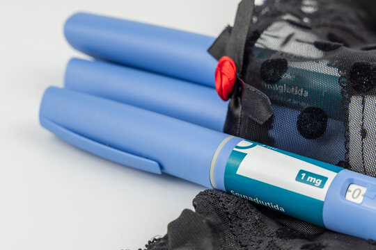Blue semaglutide medication pen pack on black lace underwear over white background for morbid obesity and metabolic health care