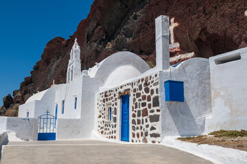Traditional Cycladic architecture built into volcanic cliff under clear blue sky in Santorini, Greece. © Andrei Tomas
