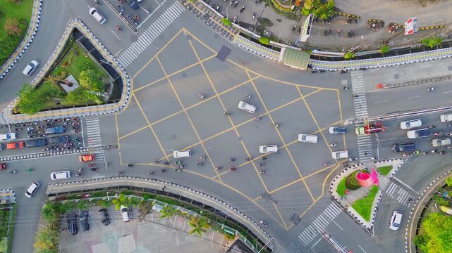 Aerial view of the busy intersection at Jalan Letnan Jendral Suprapto with vehicles and motorcycles navigating the yellow box junction in Kecamatan Samarinda Ulu, Kalimantan Timur, Indonesia.