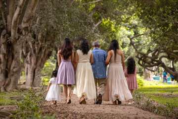 Fototapeta premium Family walking away on a path in a park during a sunny day
