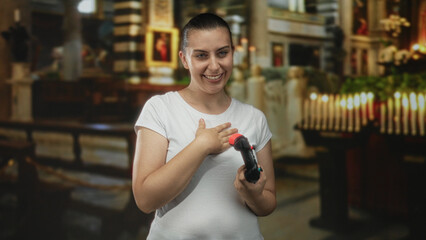 Woman laughing while holding a gamepad and placing hand on chest in a church building with lit candles and pews visible  playful amusement. © Krakenimages.com
