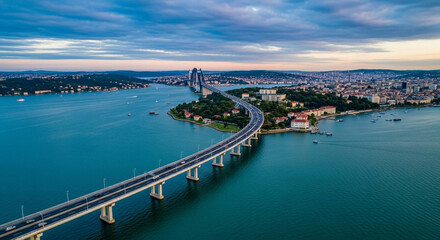 Naklejka premium Aerial view of a long bridge over water with a cityscape and boats in the background at dusk