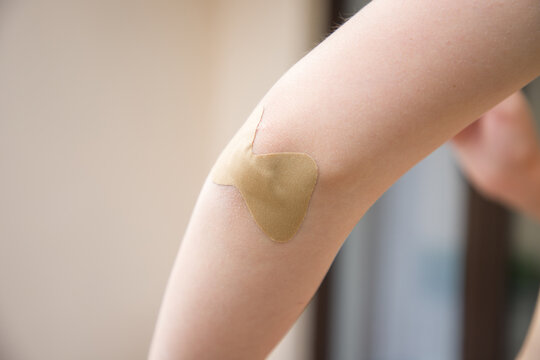 Close-up of a woman with adhesive plaster on her arm.