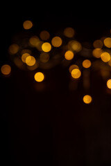 Fototapeta premium Golden bokeh lights are illuminating a dark abstract background with a blurred effect, creating a festive atmosphere for various design and decorative purposes for holidays and celebrations