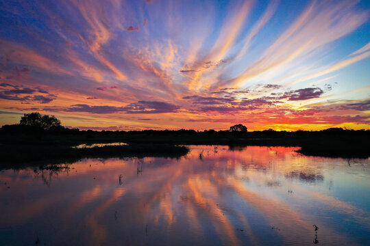 Aerial view of the vibrant sunset reflecting over the calm waters of the Thomson River near Jundah, Queensland, Australia.