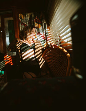 Woman sitting in striped light