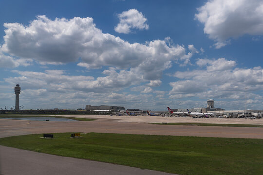 Aviation Hub: Wide-Angle Landscape View of Airplanes at Terminals Under a Cloudy Sky at Orlando International Airport, Florida
