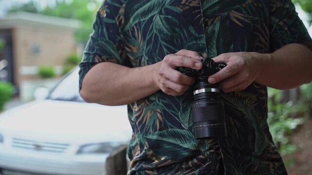 Close-up of a photographer's hands adjusting settings on a professional digital camera dials