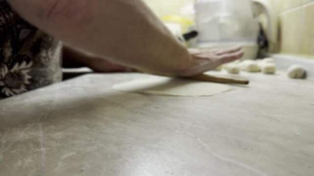 Rolling out dough with wooden rolling pin on domestic kitchen counter