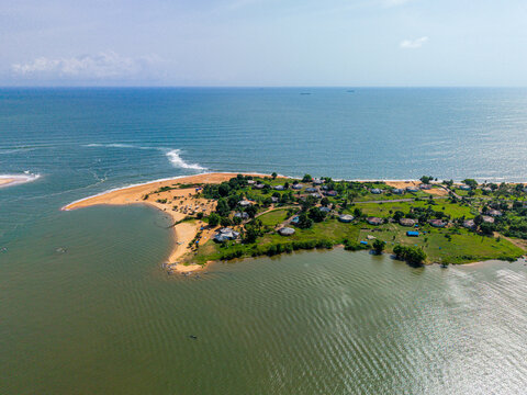 Aerial view of a coastal peninsula featuring residential buildings, lush green vegetation, and sandy beaches along the Atlantic Ocean in Monrovia, Montserrado, Liberia.