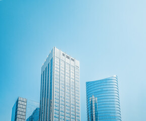 Obraz premium Modern glass skyscrapers against clean blue sky background.