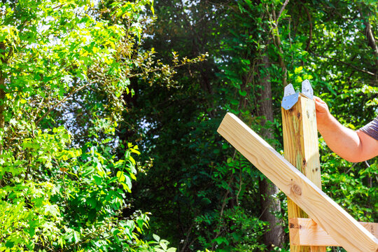 Contractor is building wooden beams frame using lumber metal brackets in construction works area