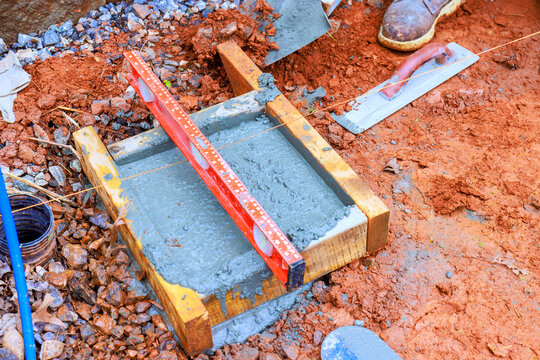 Workers level concrete slab with tools materials at construction site.