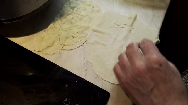 Cook unfolding flat dough and adding cheese herb filling for qutab flatbread