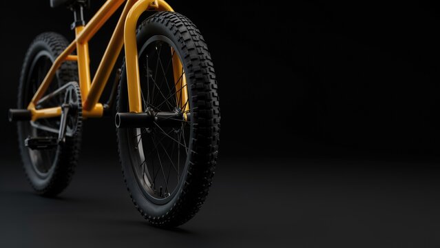 Low angle view of a bright yellow bmx bicycle frame and knobby tires on black background