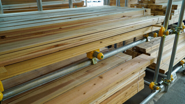 Stacked natural pine wood planks on metal storage racks