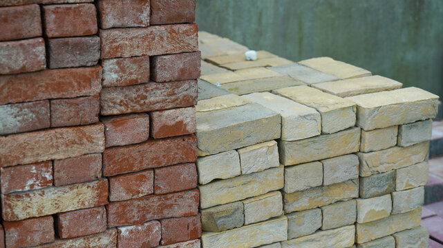 Stacked red and yellow clay bricks at a construction yard