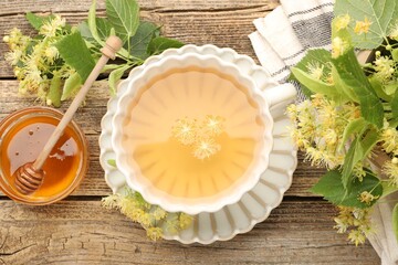 Naklejka premium Delicious linden tea in cup, honey, leaves and flowers on wooden table, flat lay