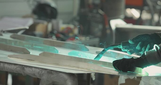 Close-up of welding an aluminum boat hull or aluminum alloys. Production of an aluminum hull for a boat. Welding process in the shop. Shipyard. Welders weld a RIB boat hull.