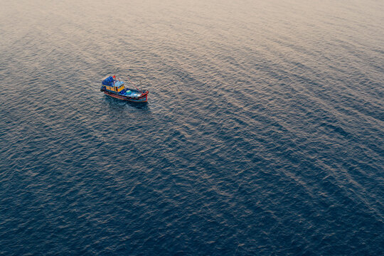 Aerial view of a small traditional fishing boat floating on the deep blue sea near Bai Hom, Vinh Hai, Khanh Hoa, Vietnam.