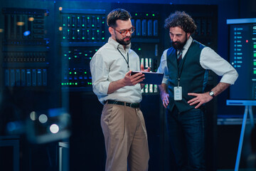 It professionals discussing data management in server room, team analyzing data center operations and network security © Zamrznuti tonovi