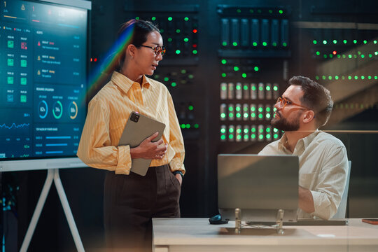 It professionals discussing data center performance metrics on screen, ensuring network security and cloud infrastructure maintenance