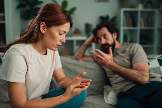 Couple having conflict at home, woman feeling stressed and sad, man talking aggressively during relationship argument