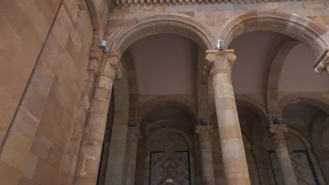 Walk through the beautiful stone colonnade of the historic Jermuk Mineral Water Gallery in Armenia, showcasing classical architecture with elegant arches and columns on a bright sunny day.

