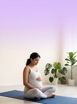Peaceful pregnant woman sitting on a yoga mat and touching her belly in a bright room with copy space