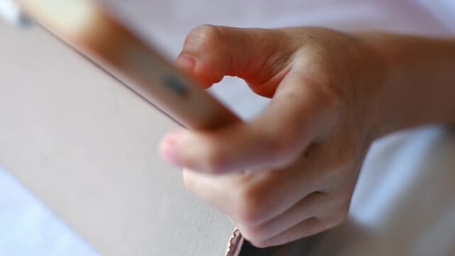 Close up of child actively playing on tablet in bed at home, tapping screen during leisure and digital entertainment time