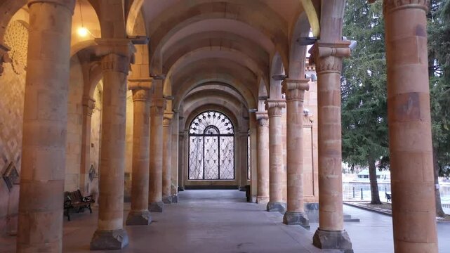 Walk through the beautiful stone colonnade of the historic Jermuk Mineral Water Gallery in Armenia, showcasing classical architecture with elegant arches and columns on a bright sunny day.

