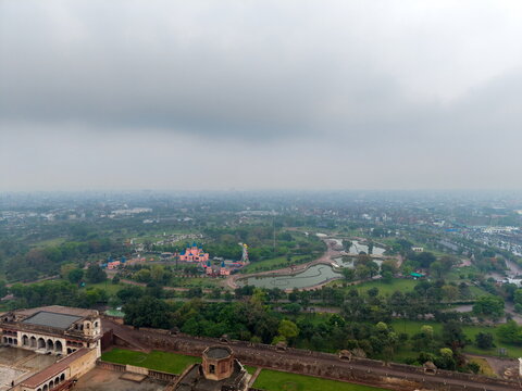 Aerial view of the historic Lahore Fort and the surrounding lush green gardens of Hazuri Bagh under a cloudy sky in Lahore, Punjab, Pakistan.